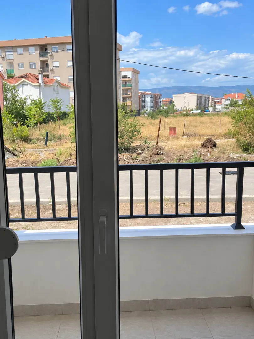 Pogled sa balkona na okolne zgrade i pejzaž.