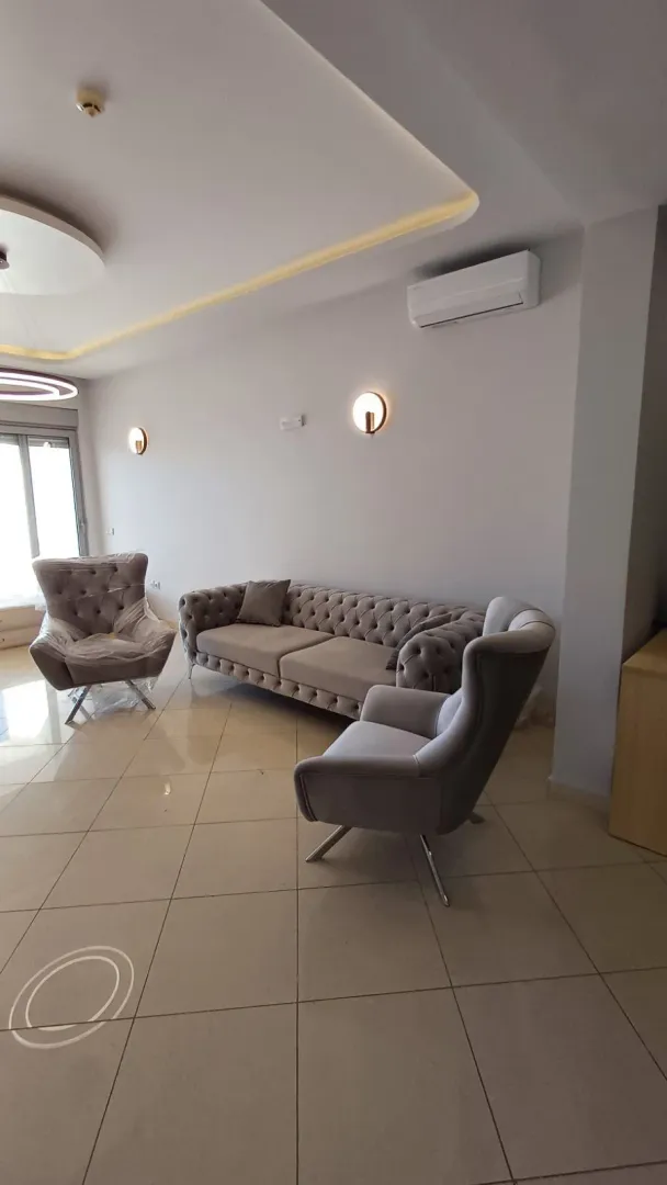 Svetao dnevni boravak opremljen modernom garniturom i foteljama.