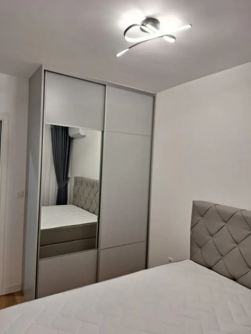 Svijetla spavaća soba sa modernim kliznim ormarom i krevetom.