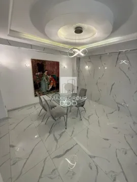 Moderna trpezarija sa staklenim stolom, sivim stolicama i mermernim pločicama na podu i zidu. - image 8
