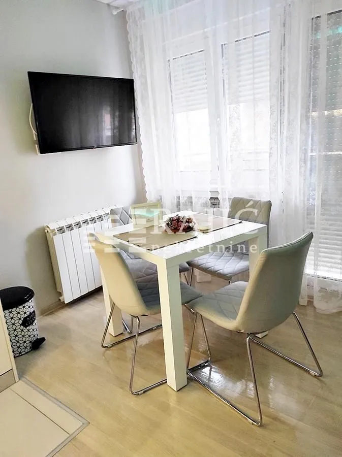 Dining area with a table, chairs, and a wall-mounted TV.
