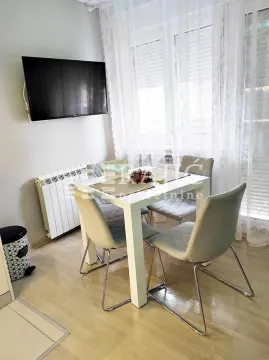 Dining area with a table, chairs, and a wall-mounted TV. - image 11