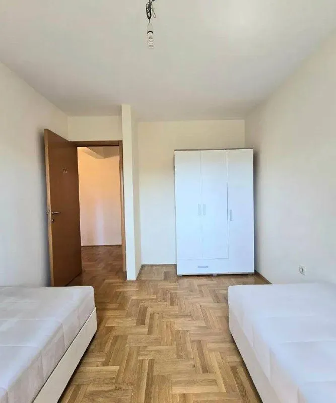 Namještena spavaća soba sa dva kreveta i garderoberom.
