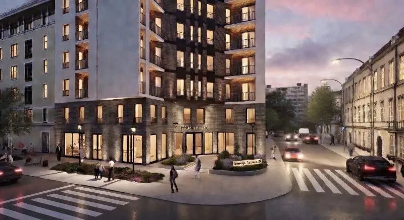 Exterior view of a modern residential building with an illuminated entrance and street in the evening.