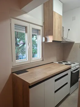 Small kitchen with wooden elements and a window overlooking greenery. - image 4