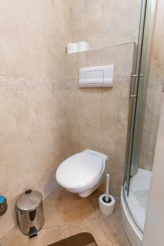 Kupatilo sa toaletom i tuš kabinom obloženo bež pločicama. - image 18