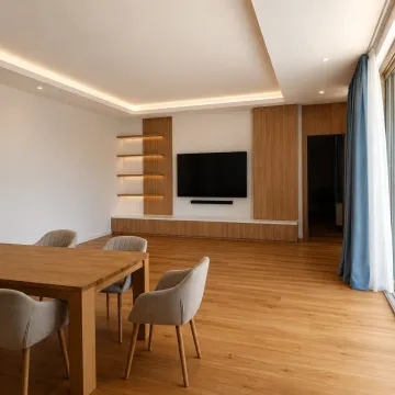 Spacious living room with wooden flooring, a dining table, and a TV wall panel. - image 6