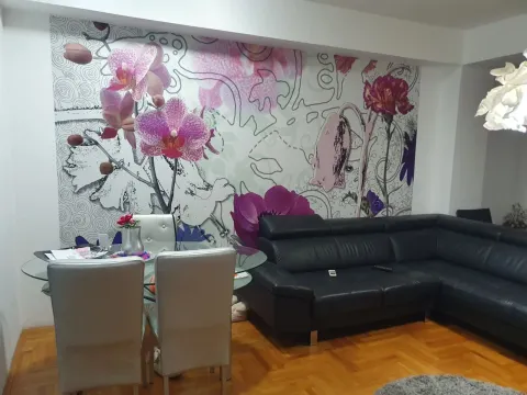 Dnevna soba sa crnom kožnom garniturom, trpezarijskim stolom i zidom sa cvijetnim motivima. - image 3