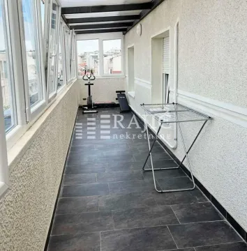 Glazed balcony with dark tiles and a clothes drying rack. - image 13