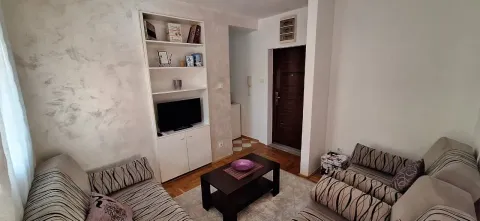 Living room with seating furniture, a coffee table, and a built-in cabinet with a TV. - image 2