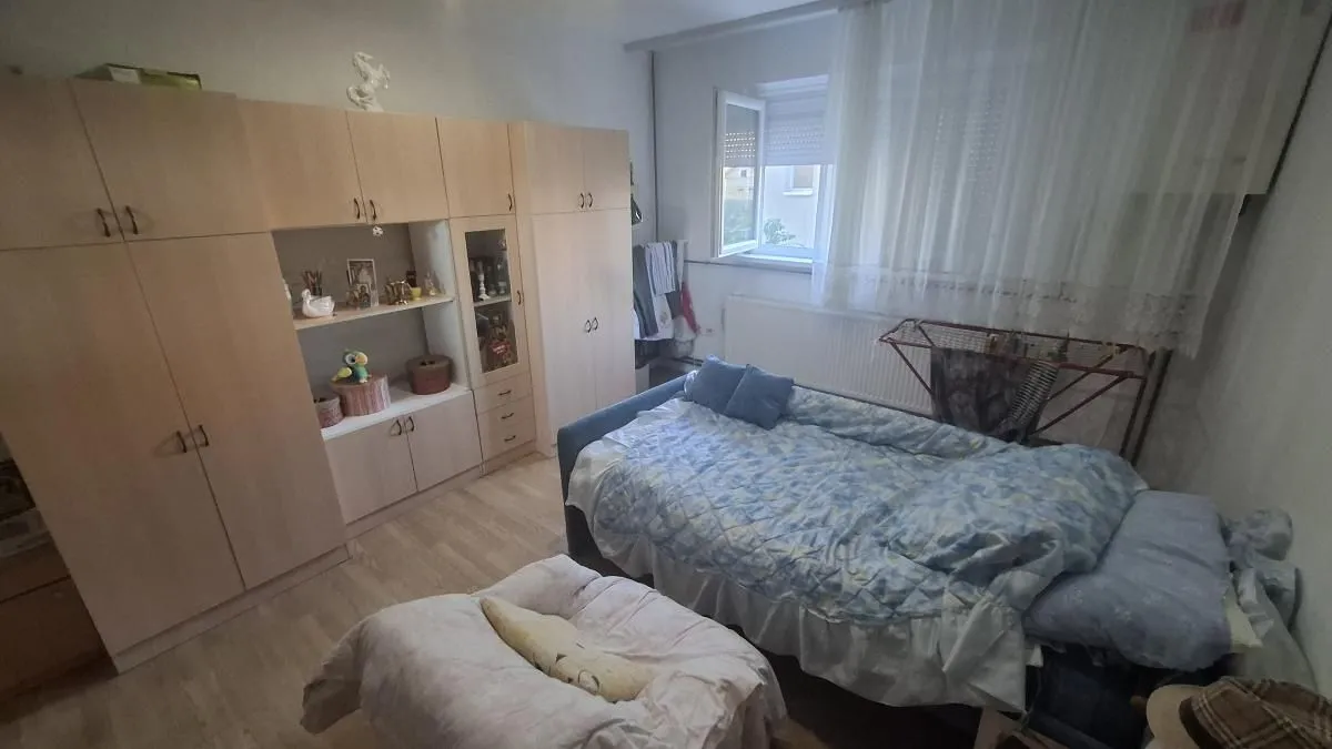 Nameštena spavaća soba sa krevetom i velikim drvenim ormarom.