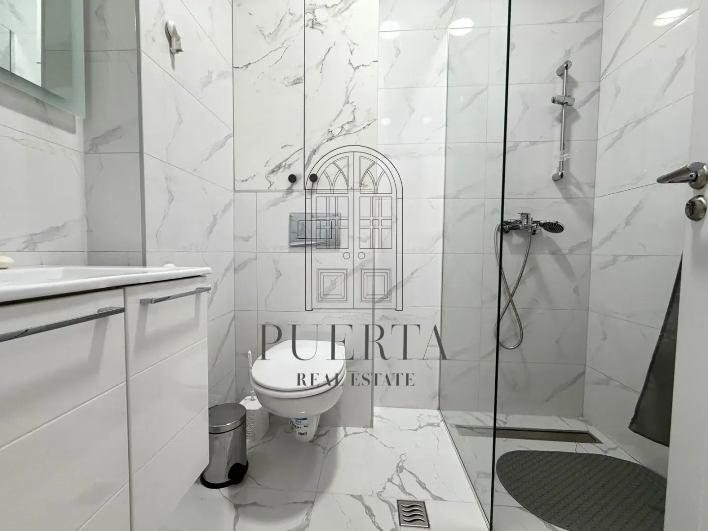 Modern renovated bathroom with a walk-in shower and white marble tiles.