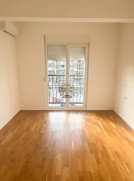 Prazna soba sa drvenim parketom i balkonskim vratima. - image 4