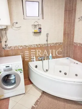 Bathroom with a corner bathtub and a washing machine. - image 14