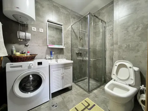 Moderno kupatilo sa tuš kabinom, veš mašinom i sivim pločicama. - image 5
