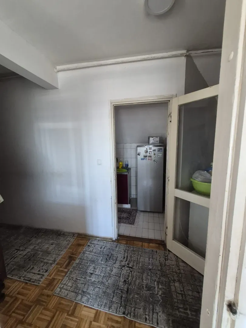 Pogled iz sobe na manju kuhinju sa frižiderom i elementima.