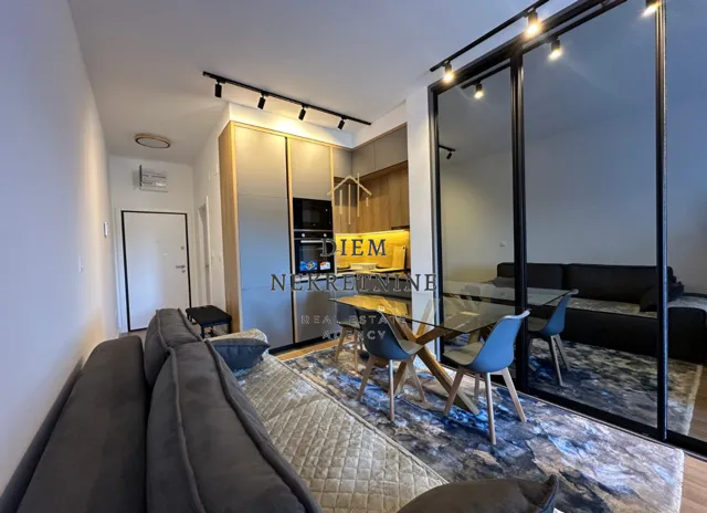 Modern living room with dining area and kitchen in the background.