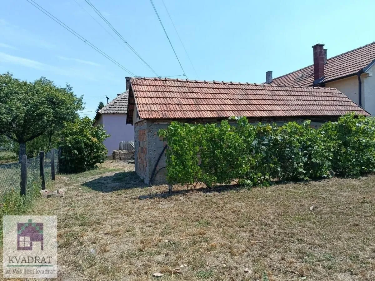 Pomoćni objekat u dvorištu sa krovom od crepa i okolnim rastinjem.