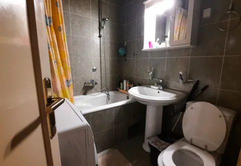 Simple bathroom with a bathtub, sink, and washing machine. - image 13