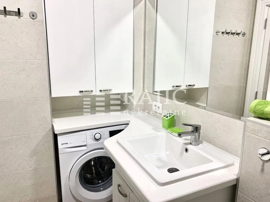 Bathroom with a washbasin, white cabinets, and a washing machine.