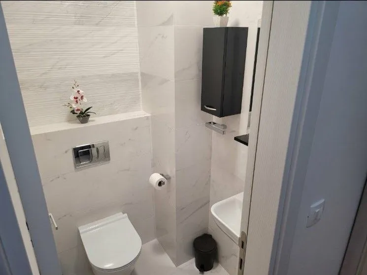 A small and modern toilet bathroom with light tiles.