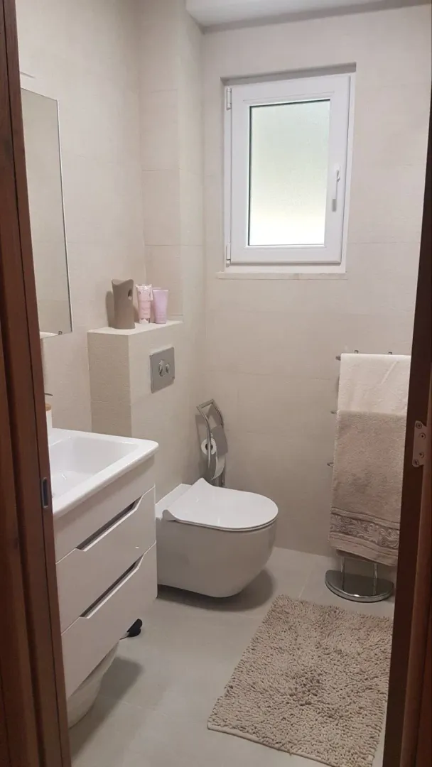 Manje kupatilo sa umivaonikom, WC šoljom i prozorom.