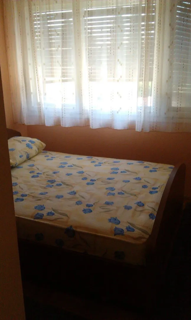 A simple bedroom with a single bed next to the window.