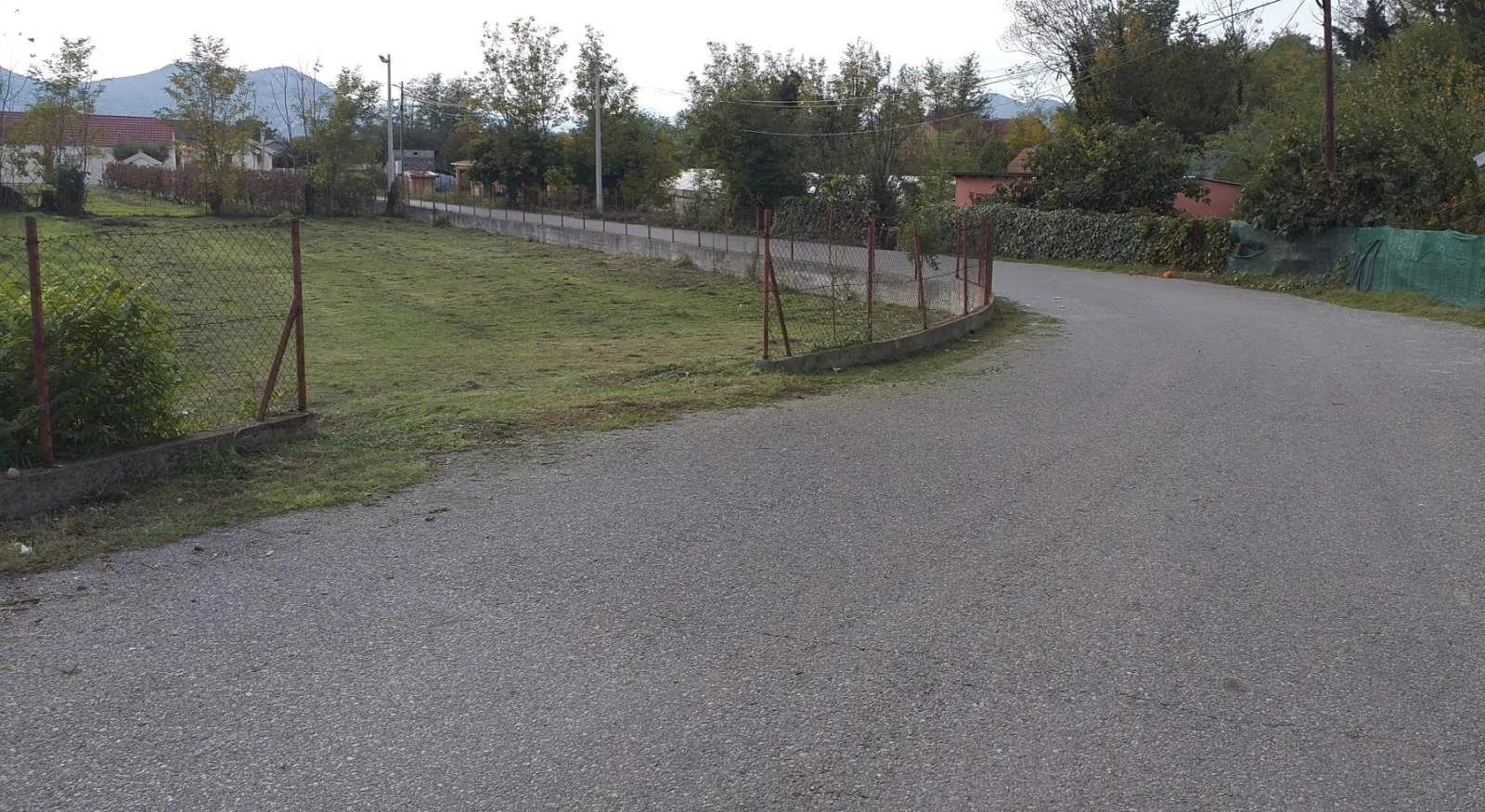 Prostran travnati plac pored asfaltnog puta.
