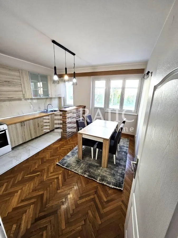 Dining area with kitchen and wooden floor.