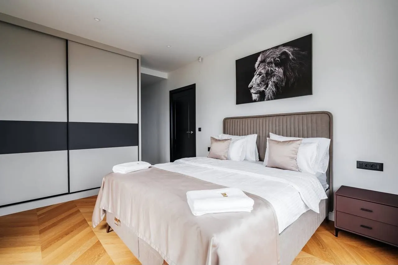 Modern bedroom with a double bed, built-in wardrobe, and parquet flooring.