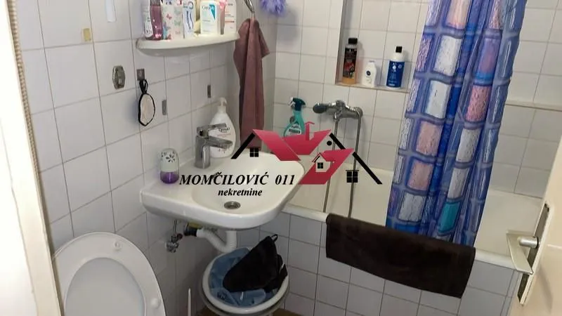 Manje kupatilo sa umivaonikom, WC šoljom i kadom sa zavesom.