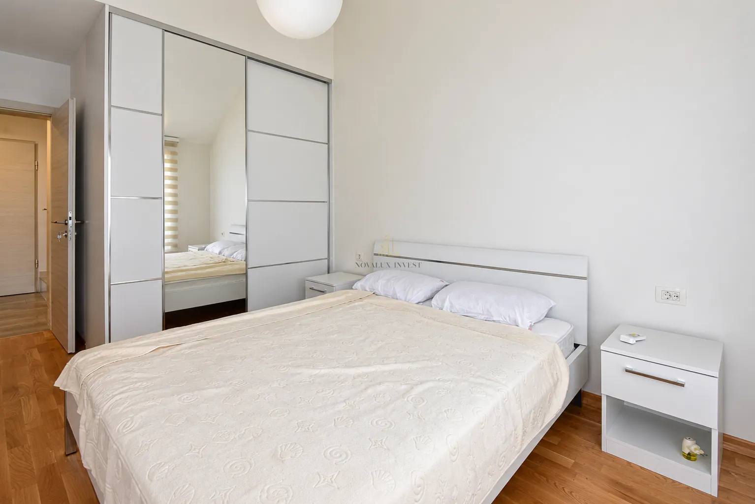 Bedroom with a double bed, white mirrored wardrobe and a bedside table.