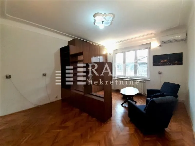 Living room with parquet flooring, wooden furniture and armchairs.