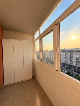 Zastakljena terasa sa bijelim ormarom i pogledom na grad. - image 14