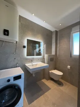 Modernly equipped bathroom with a washbasin, toilet, shower cabin, and washing machine. - image 8