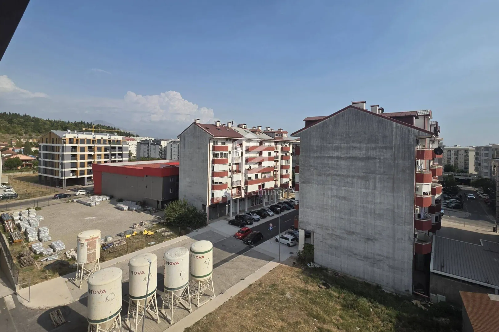 Pogled sa prozora na okolne zgrade i gradilište.