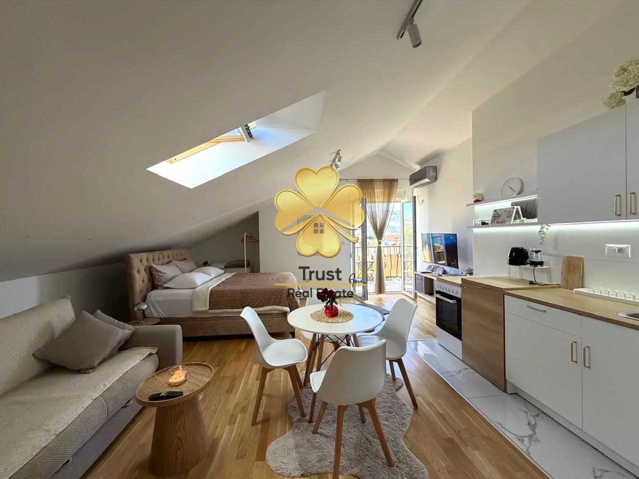 Attic apartment with an open layout featuring a living room, dining area, kitchen, and bed.