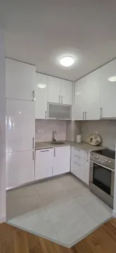 Moderna bijela kuhinja sa ugradnim uređajima i pločicama na podu. - image 4