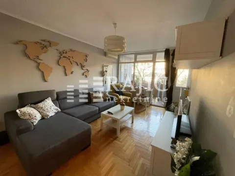 Living room with a sofa, coffee table, and a wooden world map on the wall. - image 2