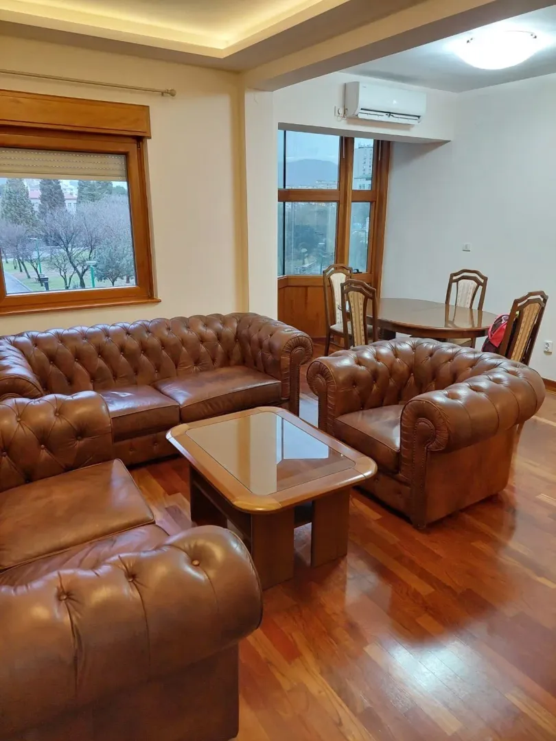 Living room with a leather sofa set, a coffee table, and a dining area in the background.