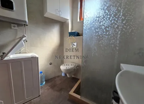 Smaller bathroom with a walk-in shower, toilet, and washing machine. - image 5