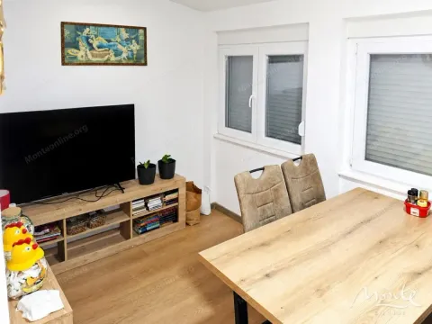 Dnevni boravak sa televizorom, drvenom komodom i trpezarijskim stolom. - image 2