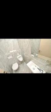Modern bathroom equipped with grey ceramic tiles, toilet, urinal, and washbasin. - image 4