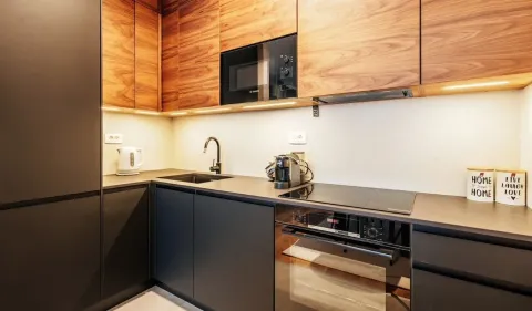 Modern kitchen with black units and wooden upper cabinets. - image 5