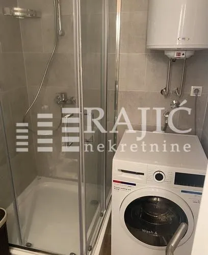 Smaller bathroom with a shower cabin and a washing machine.