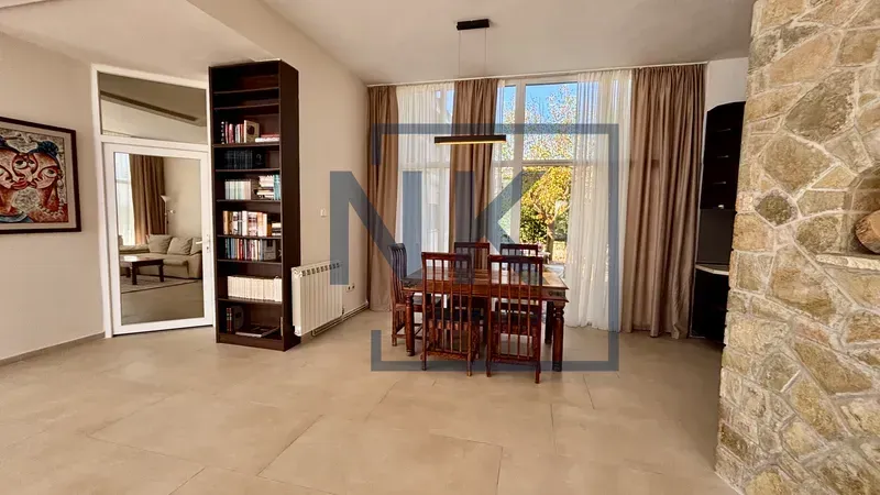 Living room with a dining area, bookcase, and large windows.