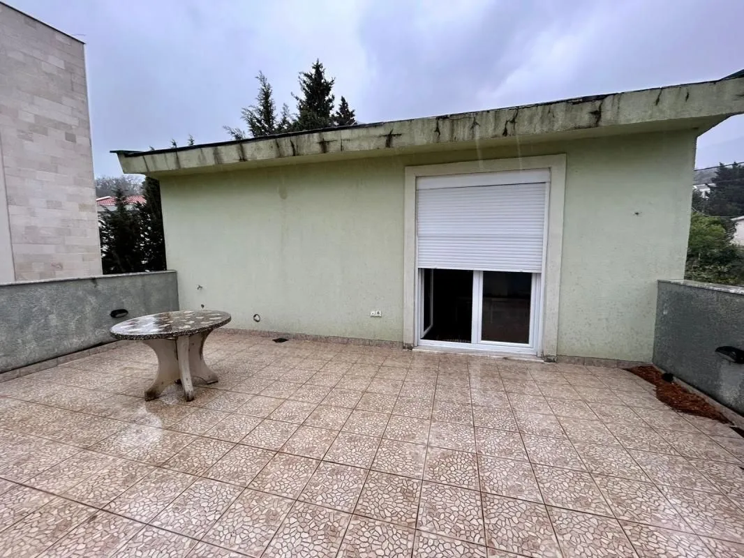 Prostrana terasa sa keramičkim pločicama i stolom.