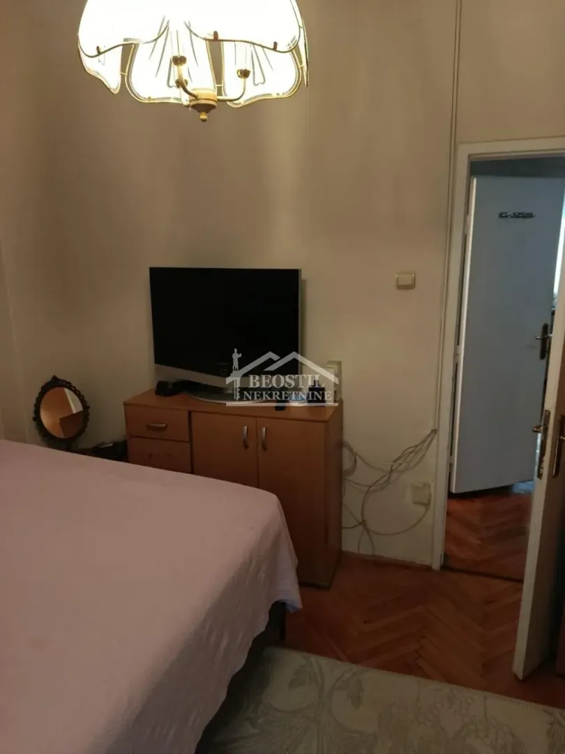 Spavaća soba sa krevetom, komodom i televizorom.