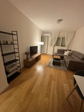 Living room with a sofa, TV unit, and wooden flooring. - image 2