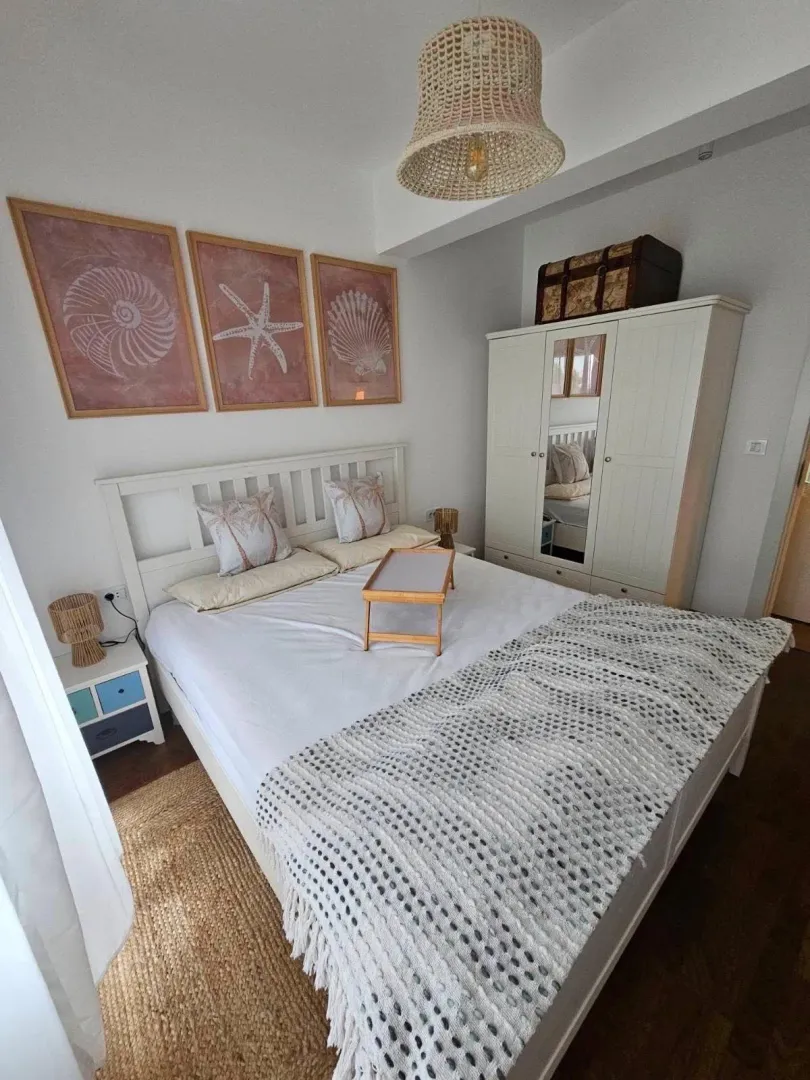 Bright bedroom with a white bed, wardrobe, and decorative pictures on the wall.